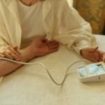 Older adult checking blood pressure at home using an electronic monitor.
