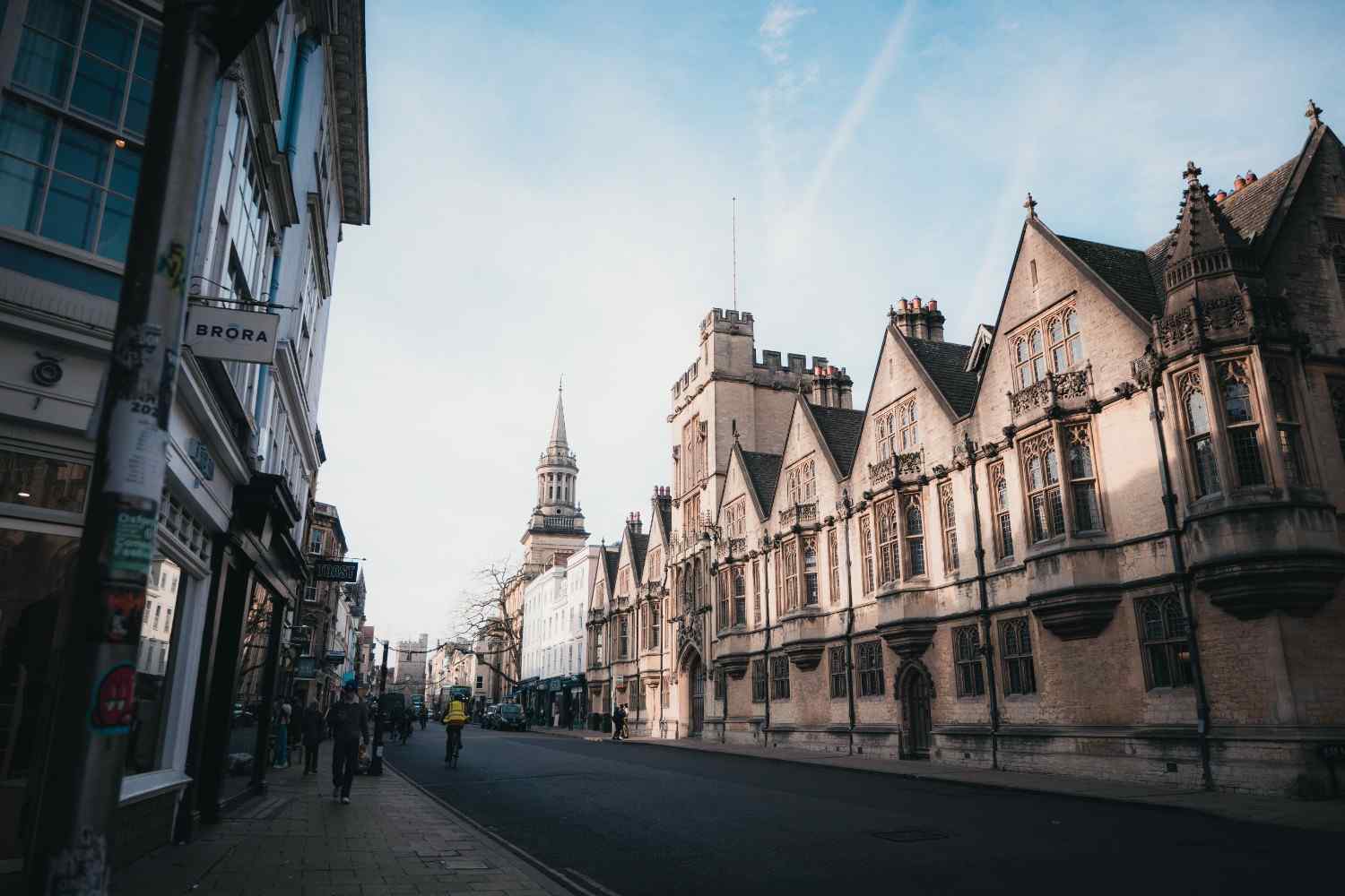 A street in Oxford featuring historic buildings and a prominent clock tower in the background.