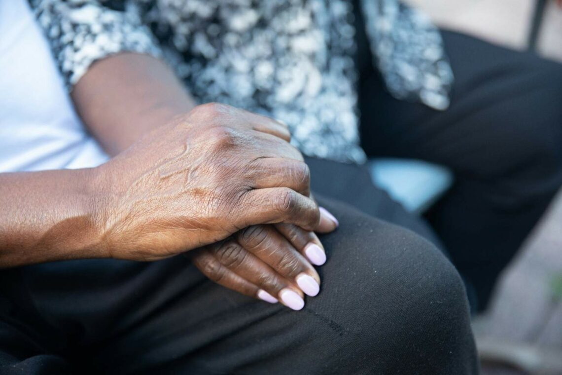 Elderly person's hands resting together on their lap, suggesting calm and dignity at home