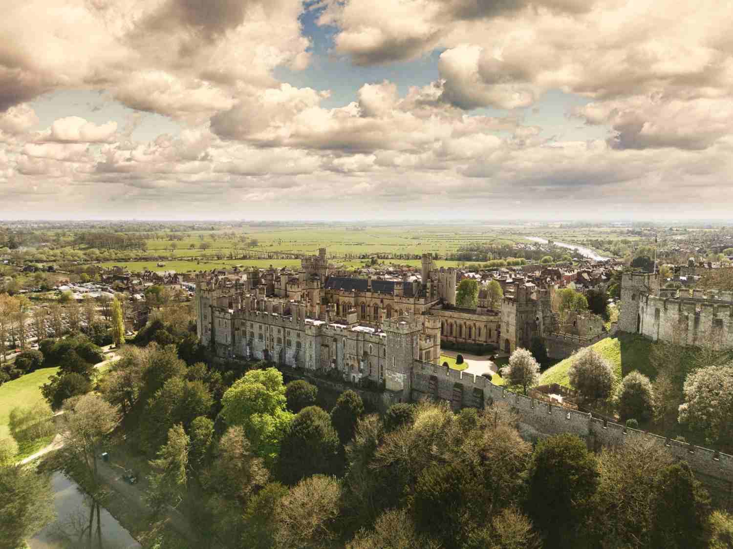 Panoramic aerial shot of Arundel Castle, emphasizing its grandeur and the lush greenery surrounding it.